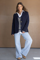 דוגמנית לובשת בלייזר כחול כהה, סוודר עם מפתח V, חולצה לבנה ומכנסי ג'ינס רחבים, לוק אופנתי לנשים