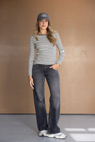 אופנת נשים: דוגמנית לובשת חולצת פסים שרוול ארוך, ג'ינס כהה וכובע מצחייה, לוק קז'ואל טרנדי.