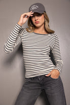 דוגמנית לובשת חולצת פסים ארוכה בצבעי שחור ולבן וכובע מצחייה אפור, עם ג'ינס שחור אופנתי לאישה