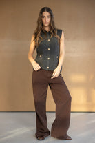 אישה לובשת מכנסיים חומים רחבים ואפודת צמר אפורה עם כפתורים, אופנת נשים חורפית