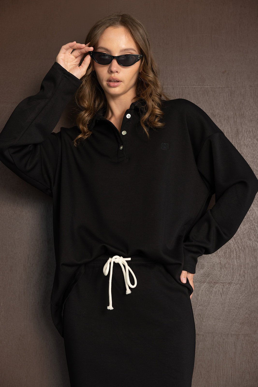 אישה עם משקפי שמש לובשת שמלת ספורט שחורה עם שרוך לבן, אופנת נשים עדכנית