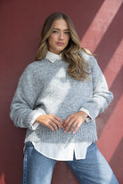 דוגמנית לובשת סוודר אפור עבה וחולצה לבנה מתחת עם ג'ינס, אופנת חורף לנשים