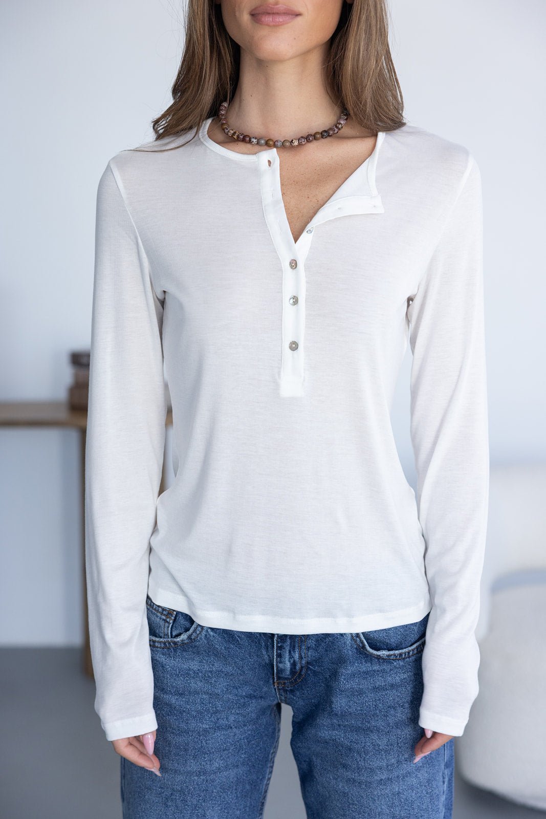 חולצת נשים לבנה עם שרוול ארוך וכפתורים, משולבת עם ג'ינס אופנתי