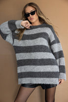 דוגמנית לובשת סוודר פסים אפור ושחור, חצאית קצרה וטייץ שחור, משקפי שמש אופנתיים