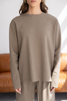 אישה לובשת סט טרנינג נשים בצבע חאקי, גזרה רחבה, בד רך, חולצה ארוכה ומכנס תואם