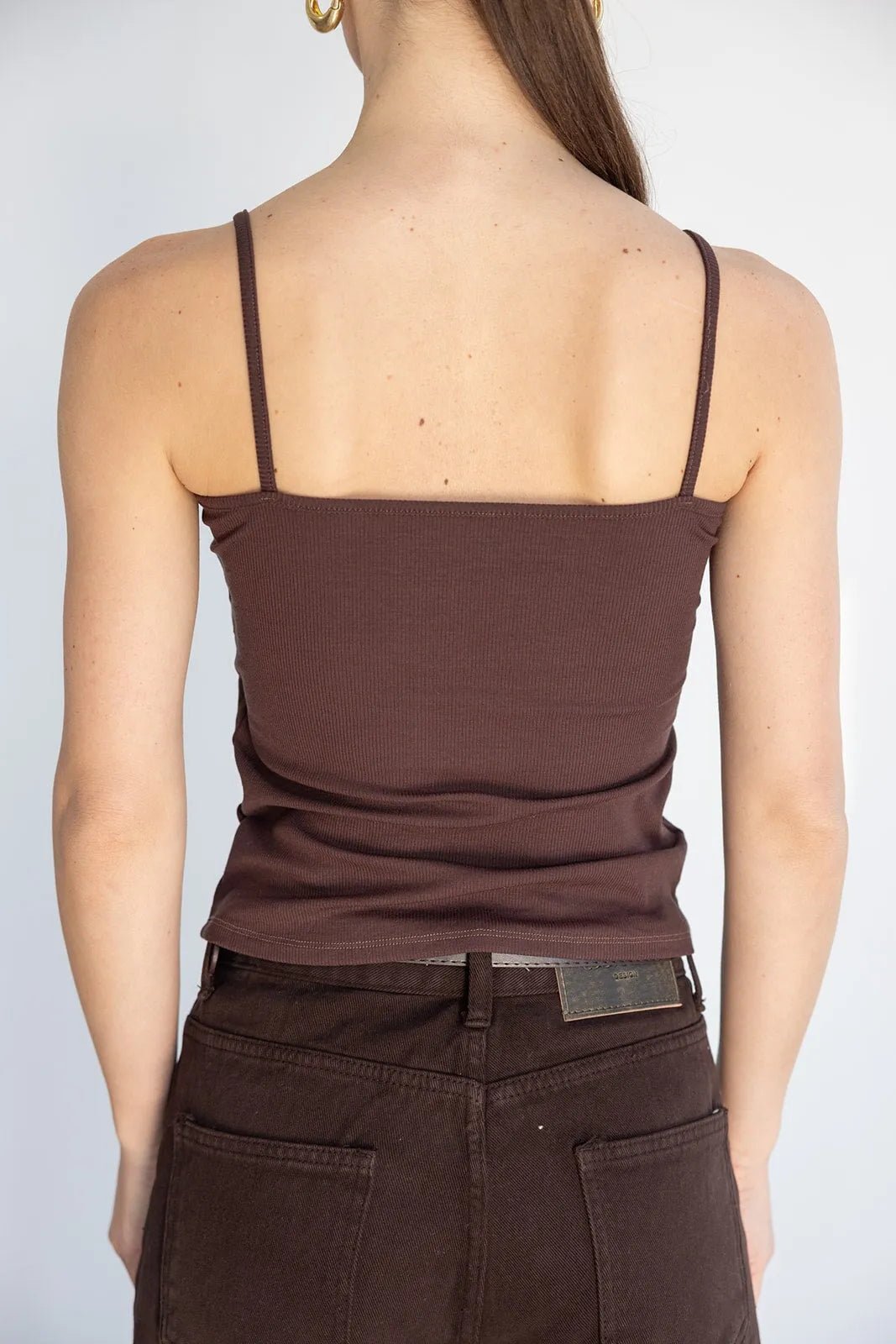 אישה עם גופיית ספגטי חומה ומכנסיים חומים, מבט מאחור, אופנה לנשים