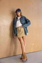 אופנת נשים צעירה: דוגמנית עם חולצה לבנה, חצאית בז', ז'קט ג'ינס, מגפיים וכובע כחול