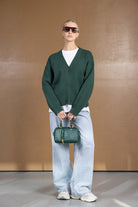 אישה עם סוודר ירוק, ג'ינס רחב, תיק יד ירוק ומשקפי שמש, אופנה לנשים צעירות