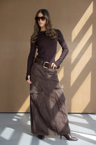 דוגמנית לובשת חולצה ארוכה חומה וחצאית מקסי חומה עם כיסי קארגו, חגורה רחבה ונעליים עקב חומות