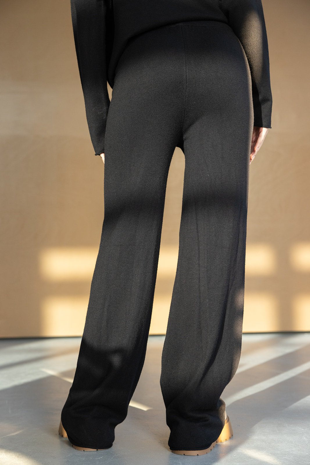 מכנסיים שחורים לנשים בגזרה רחבה, צילום חורפי באור טבעי, אופנת נשים עכשווית