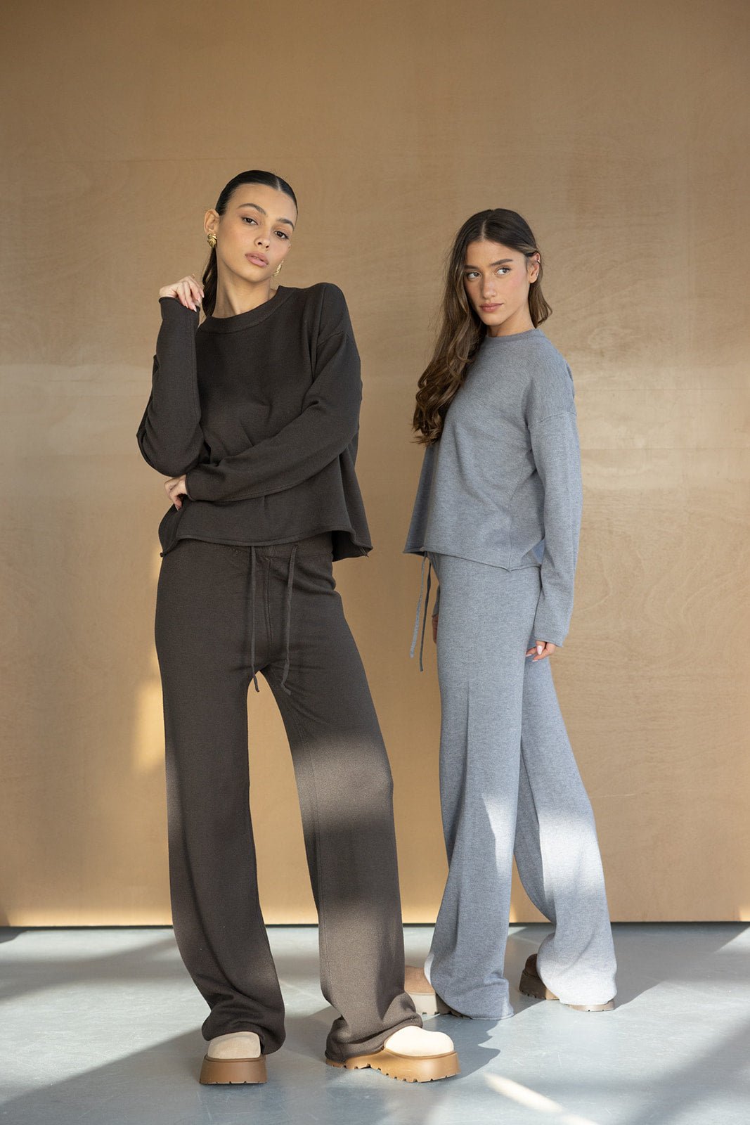 שתי דוגמניות לובשות סט טרנינג אופנתי לנשים בצבעים שחור ואפור, בגדי קז'ואל טרנדים.