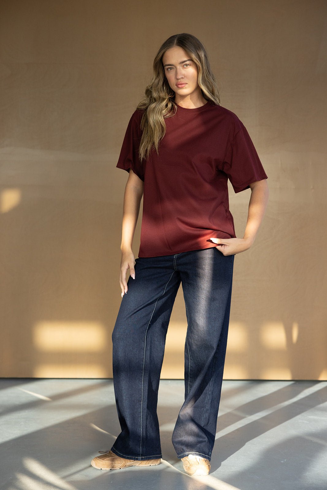 אישה בלבוש אופנתי עם חולצת טי שירט בורדו ומכנסי ג'ינס רחבים, אופנת נשים קז'ואל