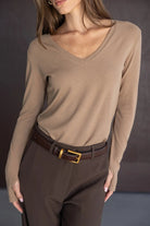 חולצת נשים בז׳ עם מחשוף V ומכנסיים חומים אלגנטיים, מראה אופנתי קז'ואל