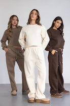 שלוש נשים מציגות טרנינג אופנתי לנשים בצבעים חום, שמנת וחום כהה, בגדי קז'ואל חורפיים