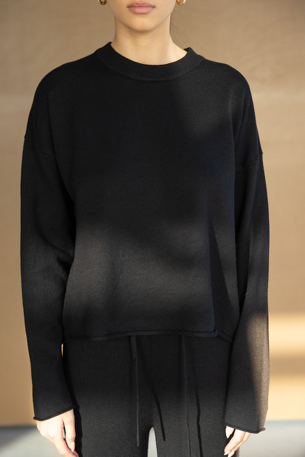 אישה לובשת סווטשירט שחור עם שרוולים ארוכים, לבוש אופנתי לנשים ונערות