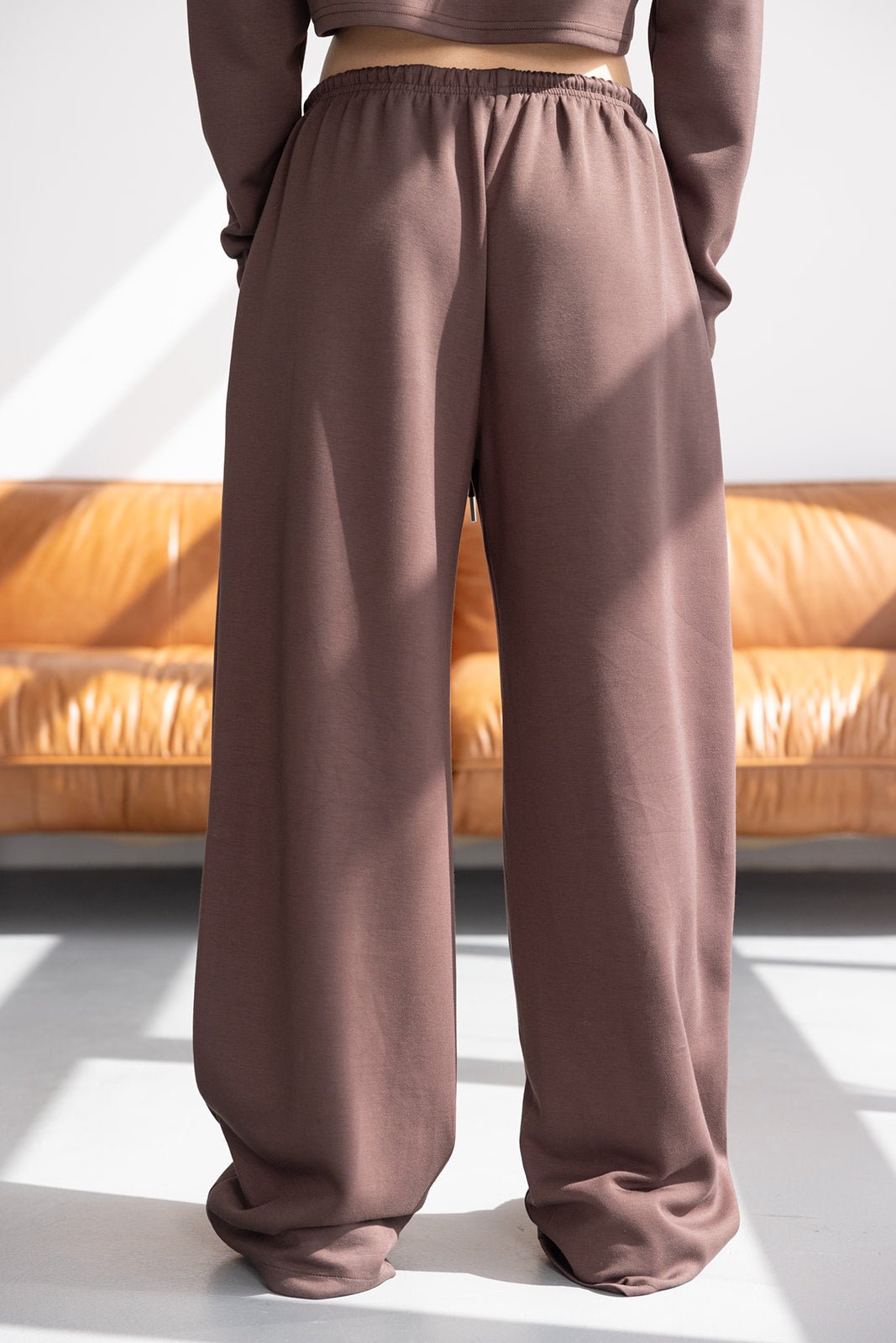 מכנסיים רחבים לנשים בצבע חום, בד נעים, גזרה גבוהה, צילום באור טבעי בסלון