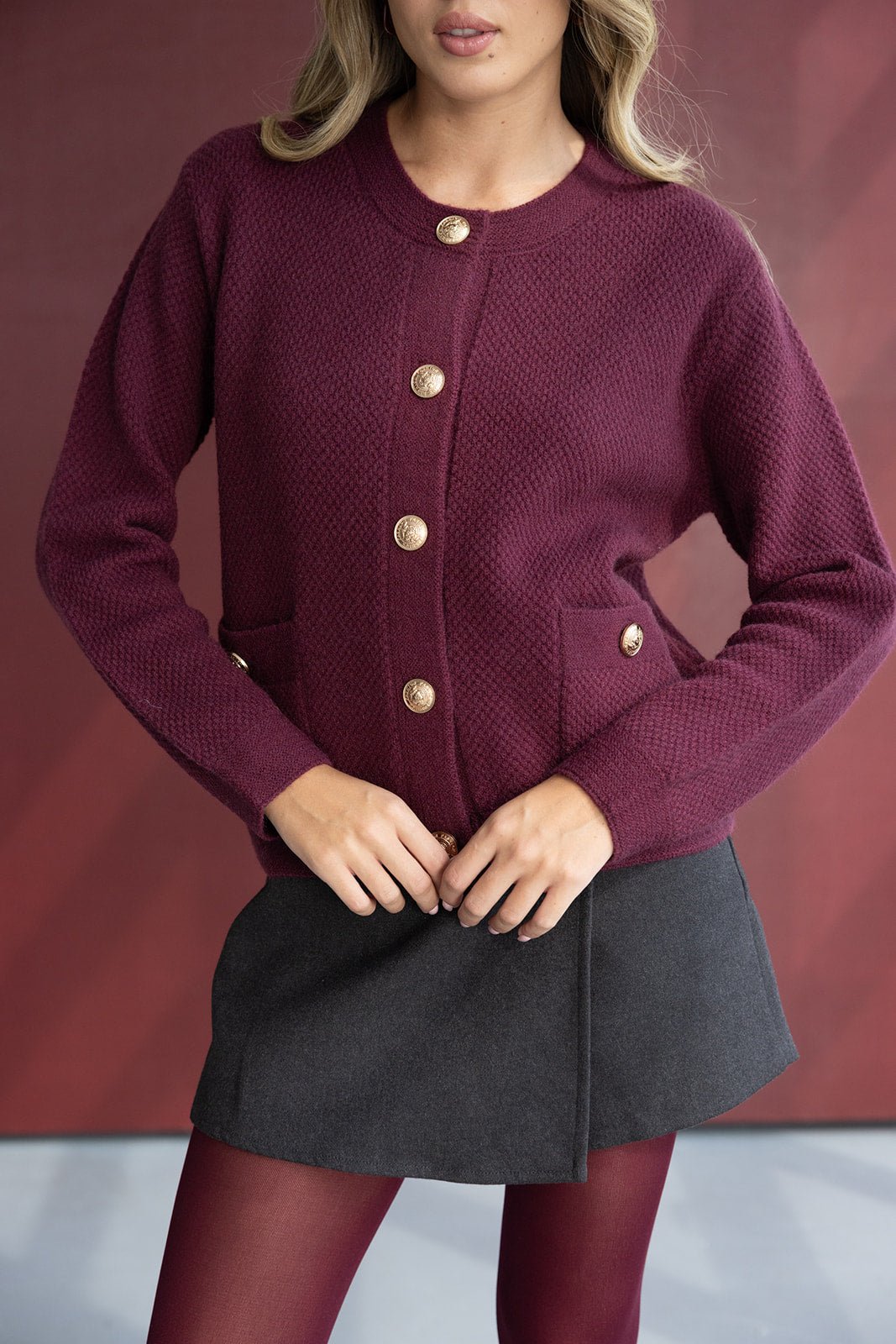 קרדיגן בורדו עם כפתורים זהב, חצאית מיני אפורה וגרביון אופנתי לאישה