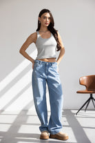 אישה לובשת גופיה אפורה ומכנסי ג'ינס רחבים אופנתיים, נעלי פלטפורמה בז', בסטודיו מואר