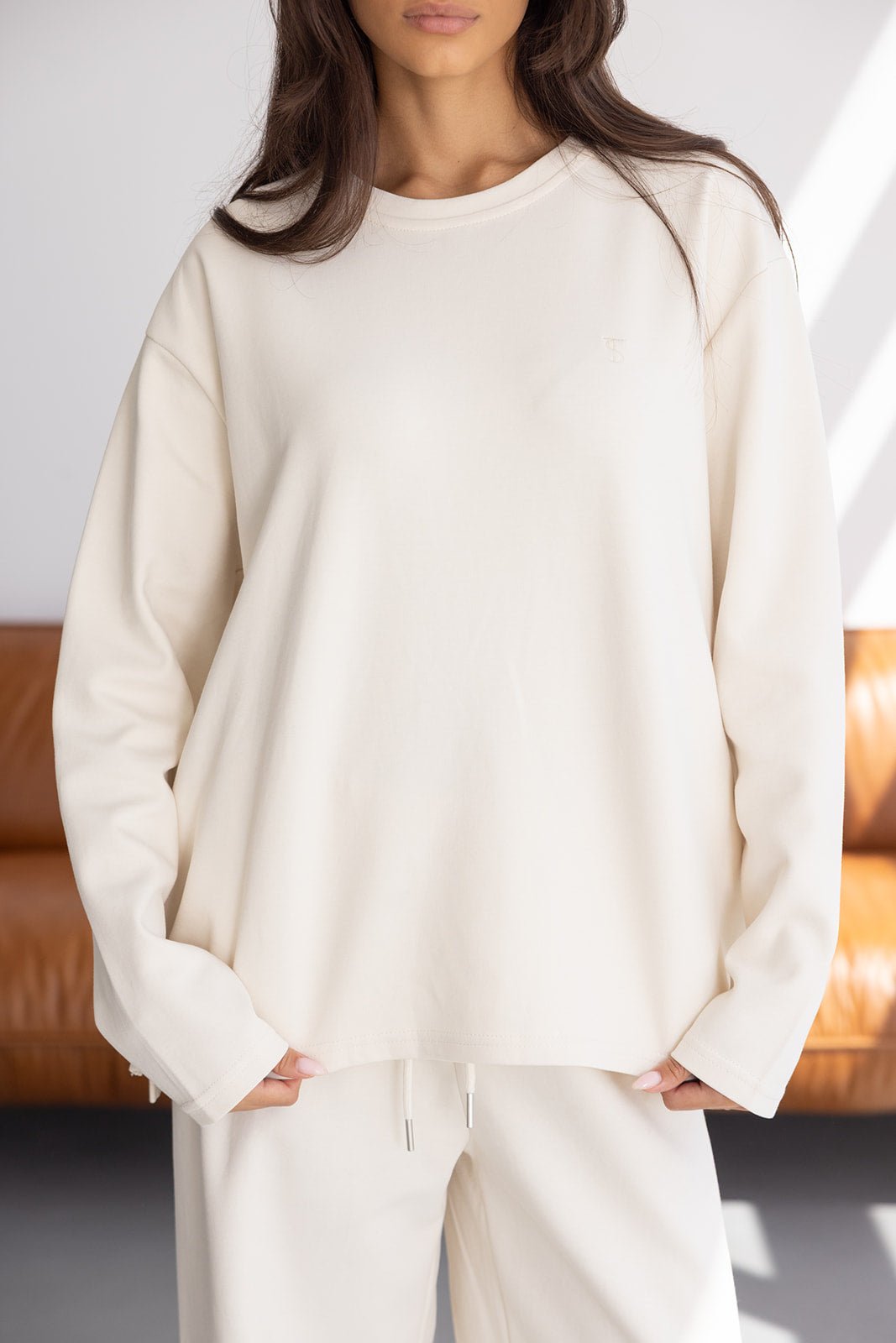 דוגמנית לובשת סט טרנינג אופנתי בצבע שמנת, חולצה ארוכה ומכנסיים תואמים, אופנת נשים