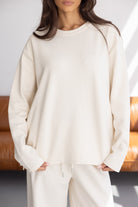 דוגמנית לובשת סט טרנינג אופנתי בצבע שמנת, חולצה ארוכה ומכנסיים תואמים, אופנת נשים