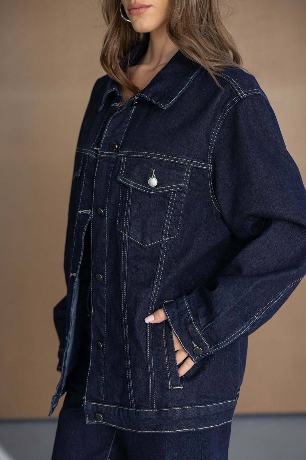אישה לובשת ג'קט ג'ינס כחול כהה אופנתי עם תפרים בולטים, צילום אופנה לנשים