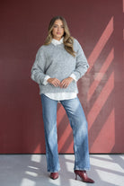 אישה עם סוודר אפור, חולצה לבנה, ג'ינס רחב ונעלי עקב בורדו, אופנת חורף לנשים