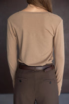 אישה עם חולצה ארוכה בצבע בז' ומכנסיים מחויטים חומים לנשים, צילום מאחור