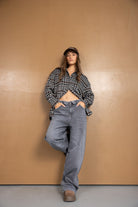 אופנת נשים צעירה, דוגמנית עם חולצת פלנל משובצת, ג'ינס רחב וכובע חום, לוק קז'ואל טרנדי