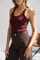 אישה לובשת גופיית בורדו מחטבת עם מכנסיים חומים חגורה, אופנה לנשים צעירות