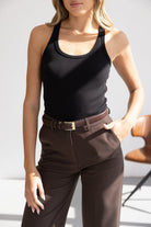 אישה לובשת גופיית טנק שחורה ומכנסיים חומים חגורת עור, אופנה לנשים צעירות