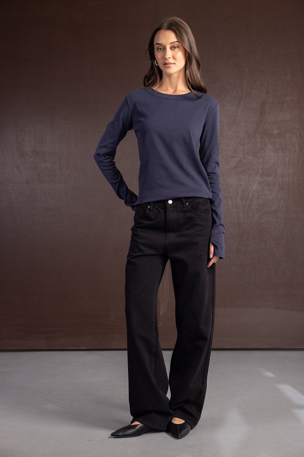 אישה לובשת ג'ינס שחור רחב וחולצת שרוול ארוך כחולה, אופנה לנשים צעירות