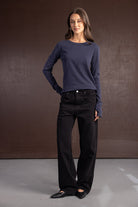 אישה לובשת ג'ינס שחור רחב וחולצת שרוול ארוך כחולה, אופנה לנשים צעירות