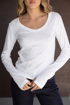 דוגמנית לובשת חולצת נשים לבנה עם שרוול ארוך ומכנסי ג'ינס, בגד אופנה לנערות