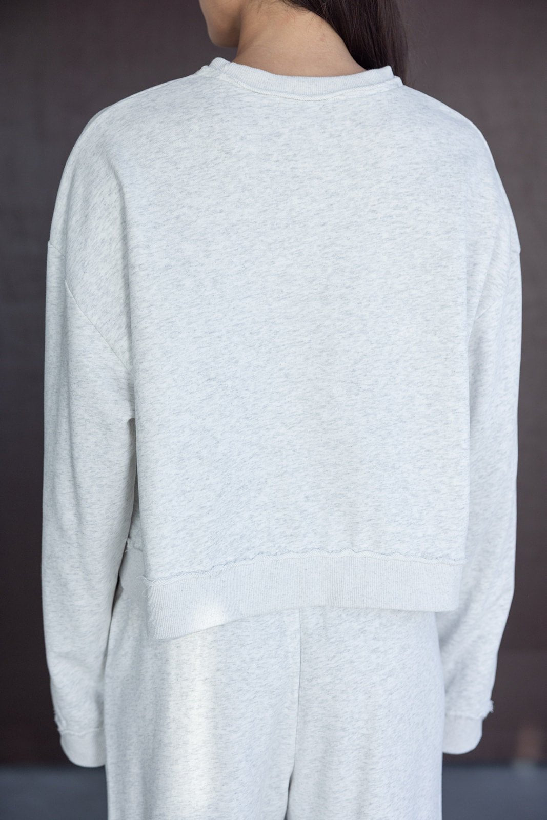 אישה לובשת סט טרנינג אפור בהיר, צילום מגב, ביגוד קז'ואל לנשים ונערות