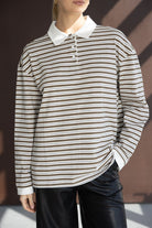 חולצת פולו ארוכה פסים חומים ולבנים לנשים, צווארון לבן, נלבשת עם מכנס עור שחור