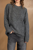 דוגמנית לובשת סוודר צמר אפור ומכנסי ג'ינס כהים, בגדי חורף לאופנה לנשים