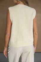 אישה לובשת וסט סרוג ללא שרוולים בצבע בז' ומכנסיים בהירים, צילום אופנה לנשים