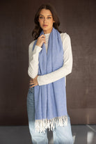 צעירה לובשת צעיף אופנתי בצבע תכלת עם פרנזים, חולצה לבנה וג'ינס, אופנת נשים חורפית