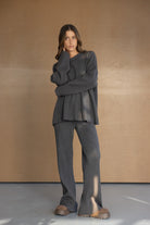 דוגמנית לובשת סט תואם מחמם בגוון אפור כהה, חולצה ומכנסיים מבד סריג בסגנון טרנדי, רקע נייטרלי
