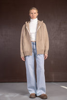 דוגמנית לובשת סוודר בז' קפוצ'ון, טופ גולף לבן, ג'ינס בגזרה רחבה ונעלי פלטפורמה חומות, אופנה לנשים