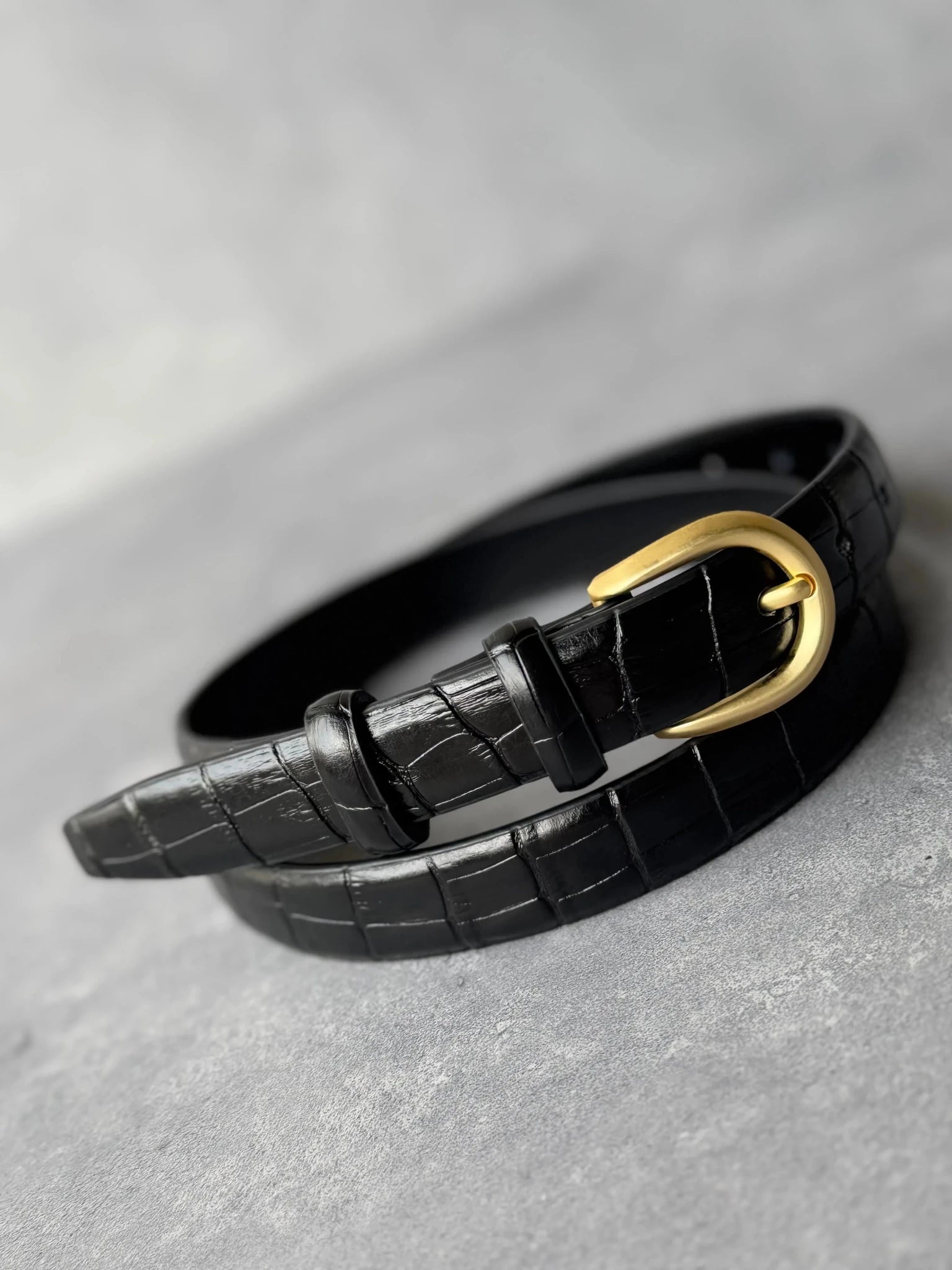 חגורת נשים אופנתית דמוי עור שחור עם אבזם זהב בעיצוב קלאסי, על רקע אפור