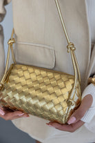 תיק צד קטן לנשים מזהב עם קלועה, נישא על ידי אישה עם בלייזר בז'