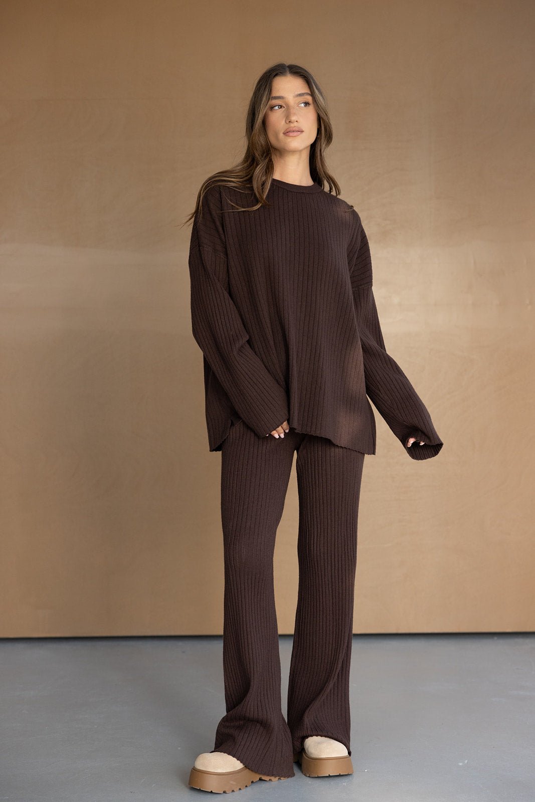 אישה לובשת סט טריקו חום מחמיא עם מכנסיים בגזרה רחבה וסוודר תואם, אופנת נשים עדכנית