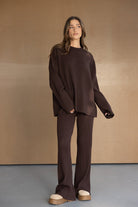 אישה לובשת סט טריקו חום מחמיא עם מכנסיים בגזרה רחבה וסוודר תואם, אופנת נשים עדכנית