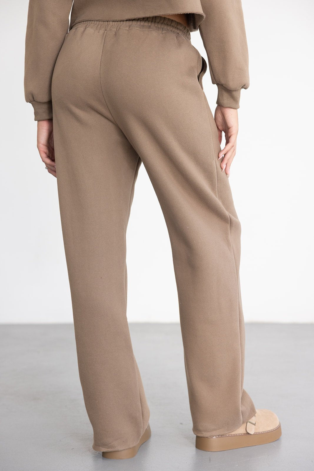 מכנסי טרנינג נשים בצבע בז' בגזרת פדלפון, על רקע לבן, אופנת נשים צעירה