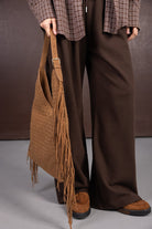 מכנסיים חומים רחבים, חולצה משובצת חומה, תיק צד חום עם פרנזים ונעליים חומות, לוק אופנתי לנשים