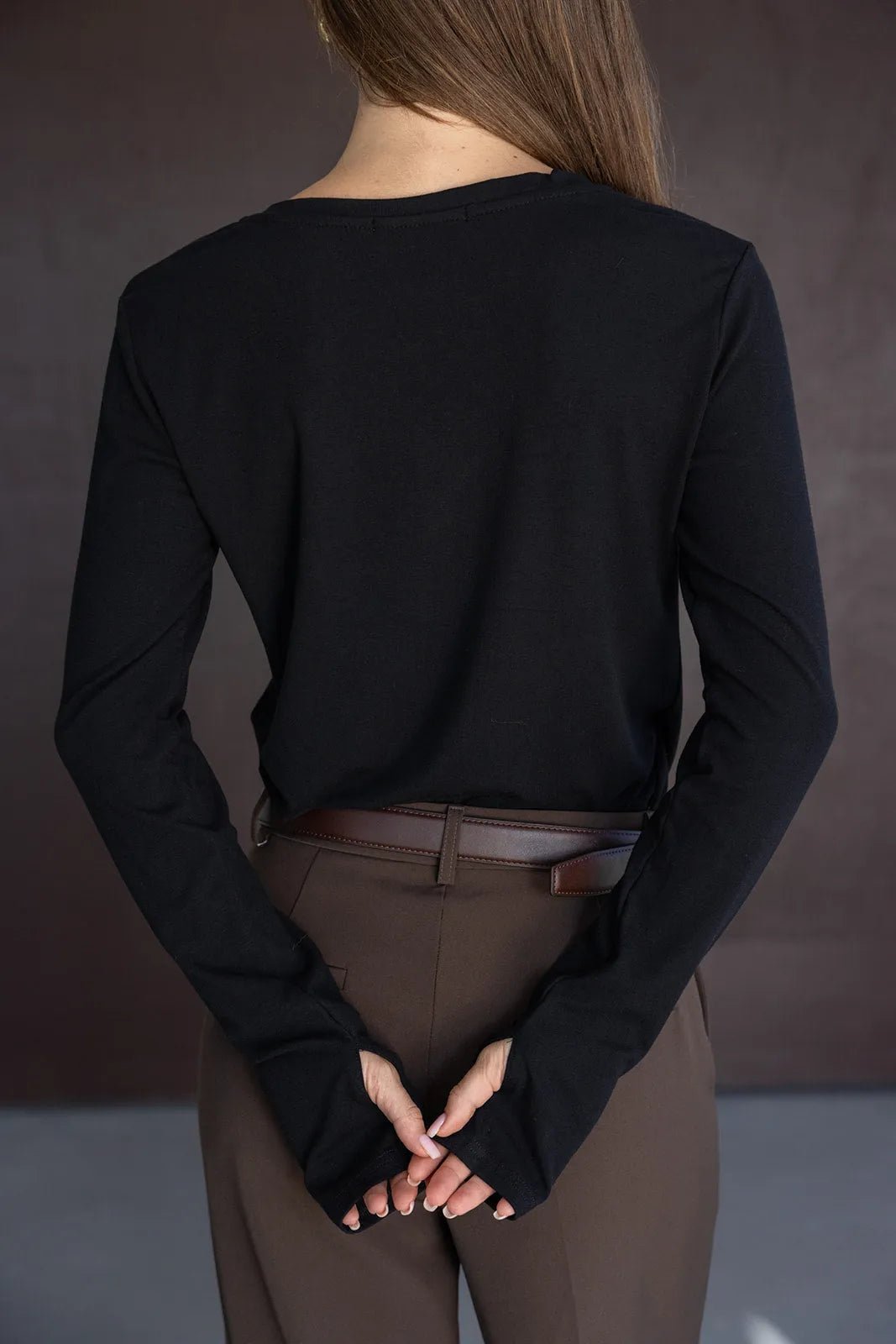 חולצה שחורה שרוול ארוך לנשים בשילוב מכנסיים חומים מחויטים עם חגורה