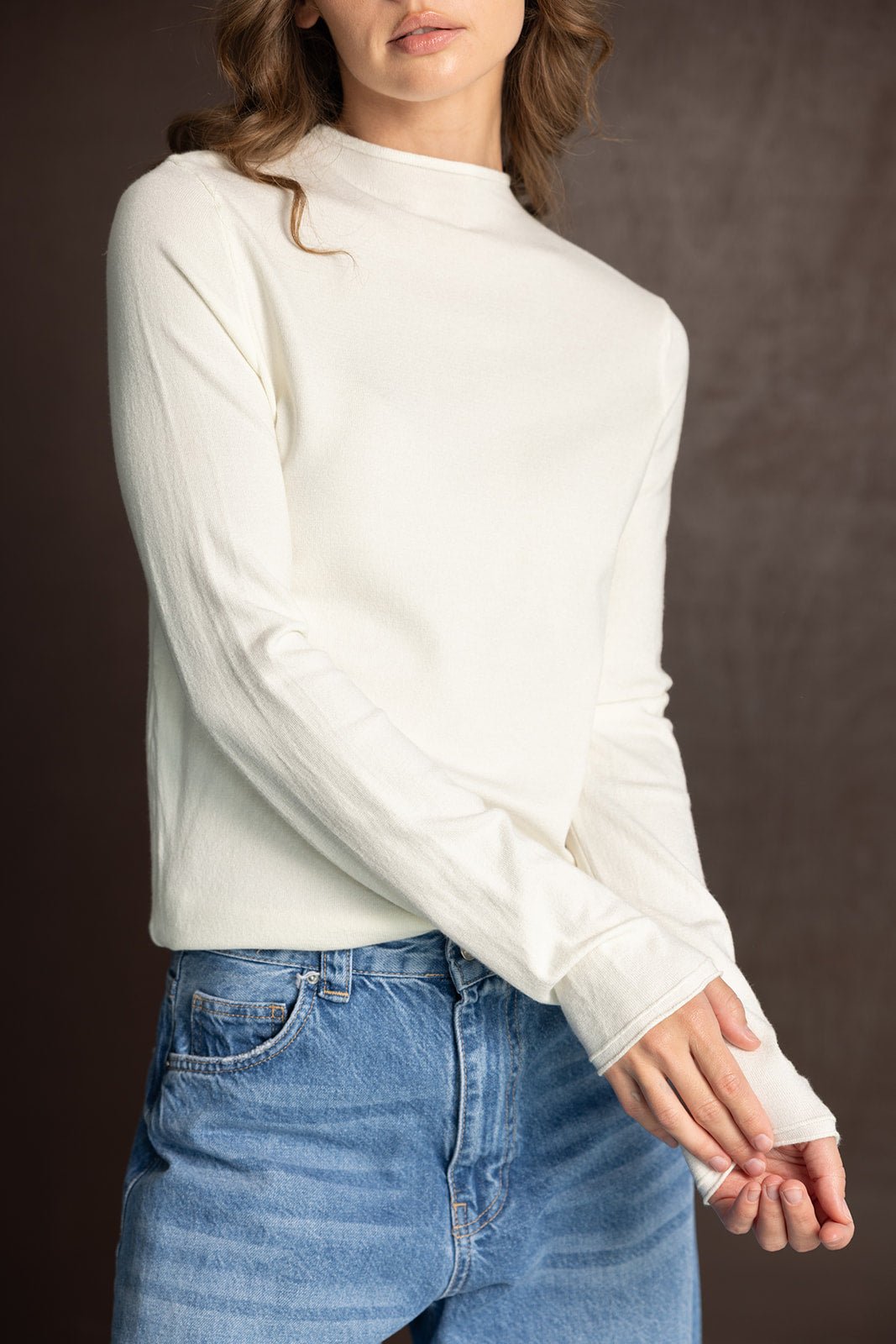 חולצת טריקו לבנה ארוכה לנשים עם גזרת צווארון גבוה, משולבת עם ג'ינס כחול אופנתי