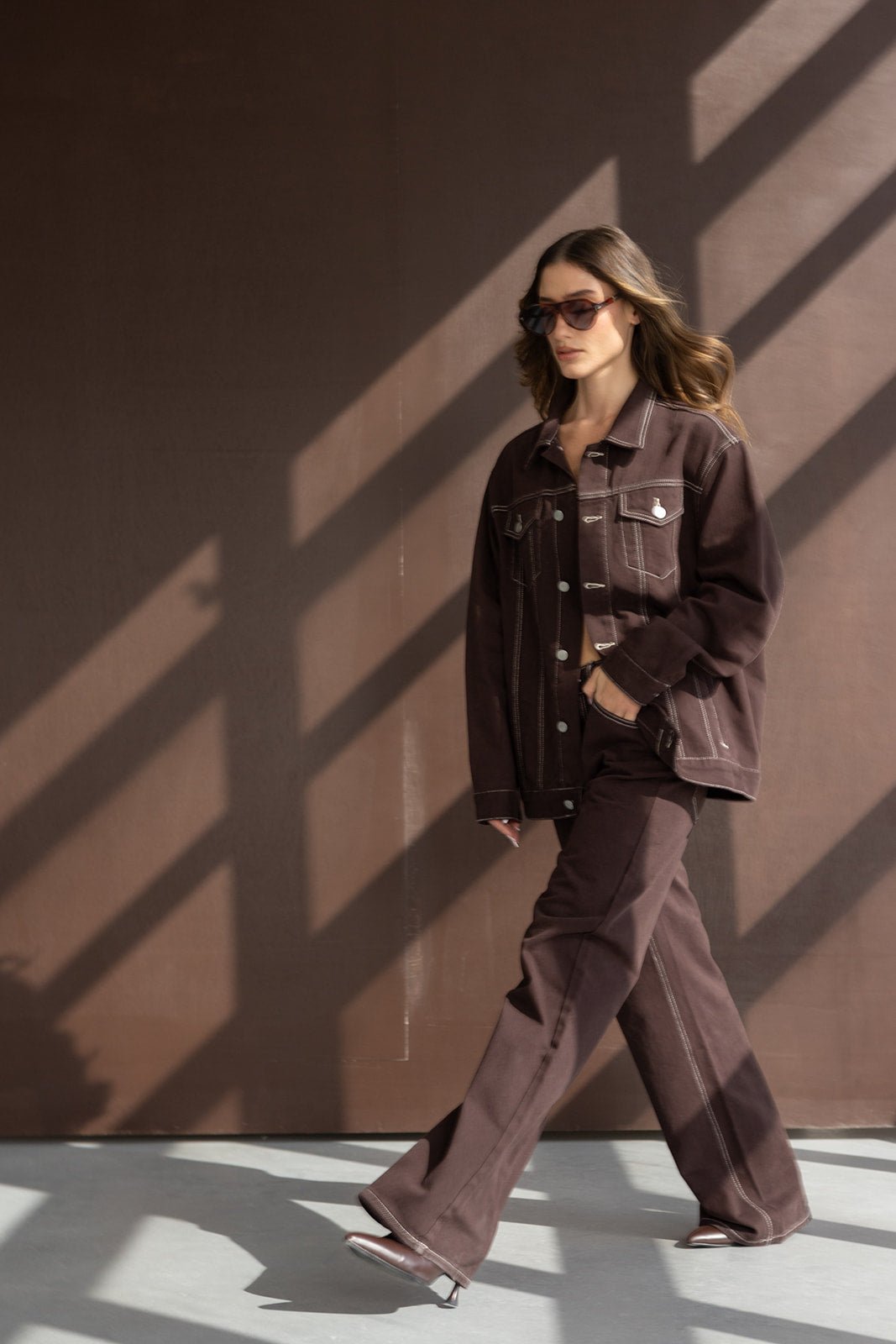 דוגמנית לובשת חליפת מכנסיים וז'קט חום לנשים, אופנה עכשווית, תאורת סטודיו