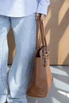 תיק יד חום לנשים, מבד דמוי עור עם ידיות כפולות, מותאם לאופנת רחוב, צולם על רקע בהיר